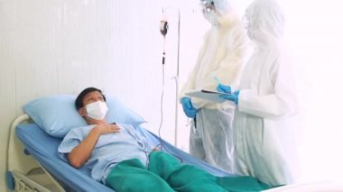 Doktor, hastane yatağında Coronavirus yüzünden öksüren hasta bir hastayla ilgileniyor. Hasta adam hastane yatağında yatıyor..