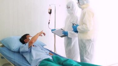 Doktor, hastane yatağında Coronavirus yüzünden öksüren hasta bir hastayla ilgileniyor. Hasta adam hastane yatağında yatıyor..