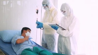 Doktor, hastane yatağında Coronavirus yüzünden öksüren hasta bir hastayla ilgileniyor. Hasta adam hastane yatağında yatıyor..