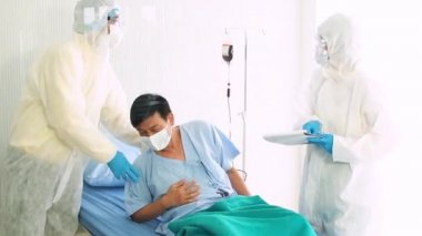 Doktor, hastane yatağında Coronavirus yüzünden öksüren hasta bir hastayla ilgileniyor. Hasta adam hastane yatağında yatıyor..
