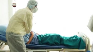 Doktor, hastane yatağında Coronavirus yüzünden öksüren hasta bir hastayla ilgileniyor. Hasta adam hastane yatağında yatıyor..
