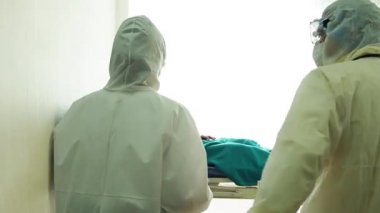 Doktor, hastane yatağında Coronavirus yüzünden öksüren hasta bir hastayla ilgileniyor. Hasta adam hastane yatağında yatıyor..