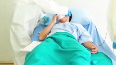 Doktor, hastane yatağında Coronavirus yüzünden öksüren hasta bir hastayla ilgileniyor. Hasta adam hastane yatağında yatıyor..