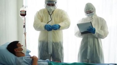 Doktor, hastane yatağında Coronavirus yüzünden öksüren hasta bir hastayla ilgileniyor. Hasta adam hastane yatağında yatıyor..