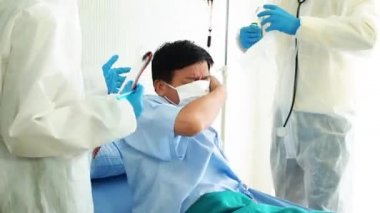 Doktor, hastane yatağında Coronavirus yüzünden öksüren hasta bir hastayla ilgileniyor. Hasta adam hastane yatağında yatıyor..