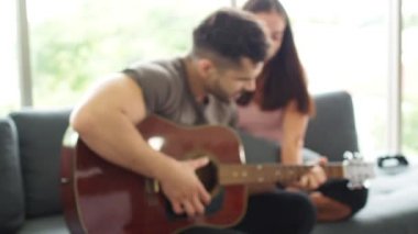Erkek, karısının kız arkadaşıyla birlikte oturma odasında soluk soluğa kalıyor. Aşık için aşk şarkıları çalan bir adam. Kutlama konsepti. Mutlu çift gitar çalıyor ve oturma odasında birlikte şarkı söylüyor..