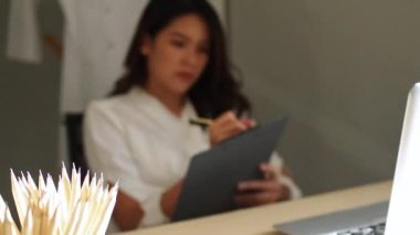 Ofiste çalışan genç bir kadın. Çekici bir ofis çalışanı masada oturuyor. İş kadını ofiste dizüstü bilgisayarda çalışmakla meşgul..