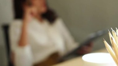Ofiste çalışan genç bir kadın. Çekici bir ofis çalışanı masada oturuyor. İş kadını ofiste dizüstü bilgisayarda çalışmakla meşgul..
