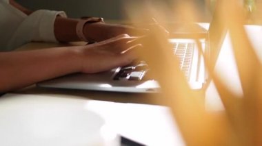 Ofiste çalışan genç bir kadın. Çekici bir ofis çalışanı masada oturuyor. İş kadını ofiste dizüstü bilgisayarda çalışmakla meşgul..