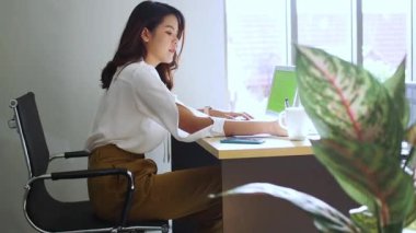 Ofiste çalışan genç bir kadın. Çekici bir ofis çalışanı masada oturuyor. İş kadını ofiste dizüstü bilgisayarda çalışmakla meşgul..