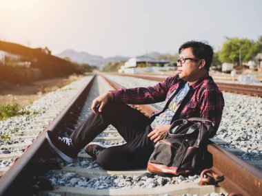 Tren istasyonundaki hippi turist Asyalı gezgin portresi. Seyahat konsepti. Seyahat ederken rahatla. Tren yolu, hippi treni yolcu seyahat süresi dolmak üzere. Tren yolu üzerinde duran adam..