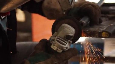Kesici dairesel metal kullanan işçiler, ışık saçan kıvılcımlara sahipler, çok çalışan ve çeliği kesen insanlar, atölyedeki kıvılcımlarla bir çeliği kesiyorlar.