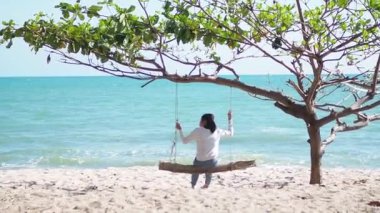 Plajda salıncak çalan kız. Uzun bir hafta sonu ve tatil tatilleri kumsalda yavaş bir hayat sürdü..