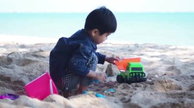 Tropik plajda oynayan bir çocuk. Aile yaz tatili. Kumsalda kum aletleriyle oynayan sevimli küçük çocuk..