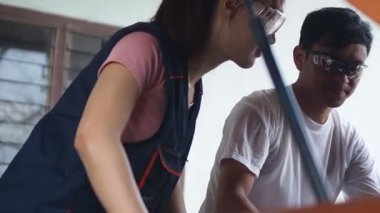 Erkek araba tamircisi garajda bir kadın çırağa ders veriyor. Erkek ve kadın, garajda dizüstü bilgisayarla konuşan iki araba tamircisi. Olgun araba teknisyeni ve asistanları garajda iş konuşuyorlar..