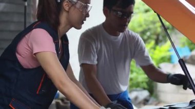 Erkek araba tamircisi garajda bir kadın çırağa ders veriyor. Erkek ve kadın, garajda dizüstü bilgisayarla konuşan iki araba tamircisi. Olgun araba teknisyeni ve asistanları garajda iş konuşuyorlar..