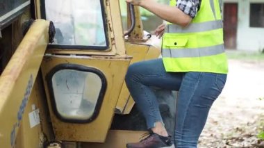 Ağır kazıcı kullanan bir kadın, büyük, modern bir kamyonun kabininde oturuyor.