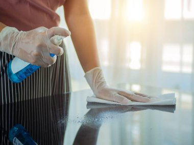 COVID-19 içeriyi sterilize ediyor. Ev masasını temizlemek mutfak masasının yüzeyini dezenfektan sprey şişesiyle temizlemek yüzeyi havlu ve eldivenle yıkamak..