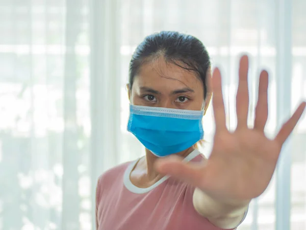 Woman wearing mask for protection from disease and show stop hands gesture for stop corona virus outbreak. Global call to stay home, Coronavirus concept. stopped without signs.