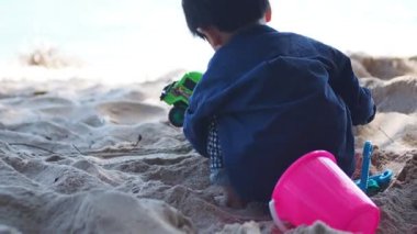 Tropik plajda oynayan bir çocuk. Aile yaz tatili. Kumsalda oyuncaklarla oynayan sevimli küçük çocuk..