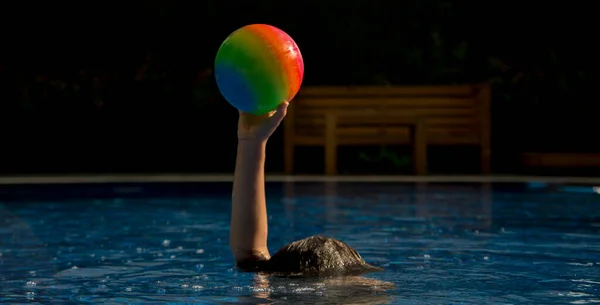 Renkli top çocuğun elinde duruyor.