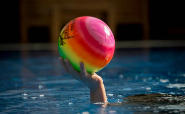 Renkli top çocuğun elinde duruyor.