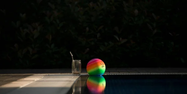 Havuz kenarında renkli top ve kahve kupası.