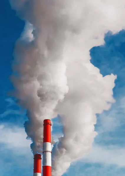 Environmental pollution, environmental problem, smoke from the chimney of an industrial plant or thermal power plant on a background of blue sky