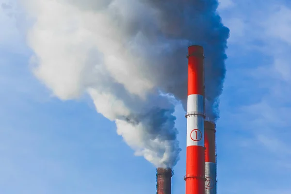 Environmental pollution, environmental problem, smoke from the chimney of an industrial plant or thermal power plant on a background of blue sky