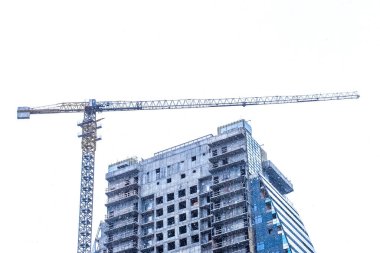 Kule vinci ve kışın karlı inşaat alanında tamamlanmamış yeni şehir binası