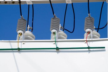 Mavi gökyüzündeki yüksek voltajlı alt istasyonun porselen izolatörleri.