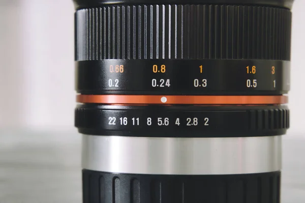 The close photo of 12 mm manual focus lens for mirrorless APSC cameras on white background. Aperture scale and focus distance scale markings on optical lens.