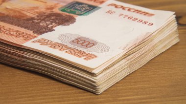 Ahşap yüzeyde yatan beş bininci banknotta bir yığın Rus parası var. Zenginlik, kâr, iş ve finans kavramı.