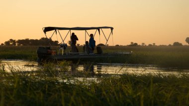 Turistler Botsvana Afrika 'daki Chobe Ulusal Parkı' nda safaride teknedeler.. 