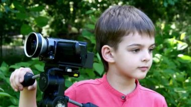 Genç oğlan video kameraya yeşil park arka plan üzerinde görünüyor..
