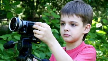 Genç oğlan video kameraya yeşil park arka plan üzerinde görünüyor..