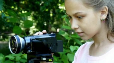 Genç kız video kameraya yeşil park arka plan arka plan üzerinde görünüyor..
