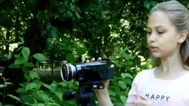 Genç kız video kameraya yeşil park arka plan arka plan üzerinde görünüyor..