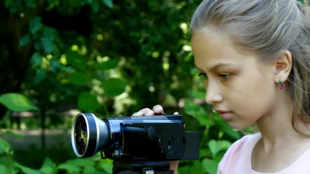 Young girl looks into video camera on background of green park background. — Stock Video