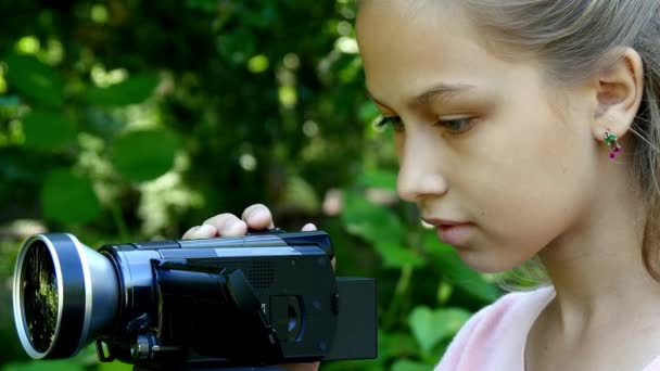 Young girl looks into video camera on background of green park background. — Stock Video