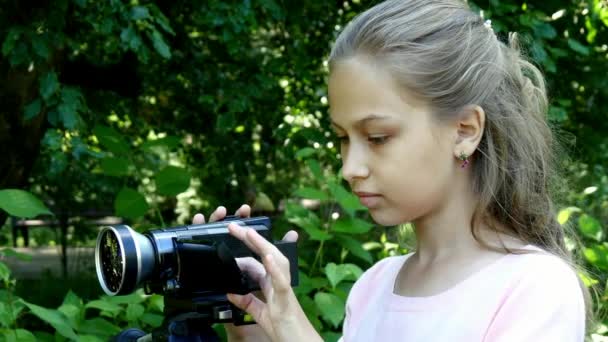 Chica joven mira en la cámara de vídeo en el fondo de fondo verde parque . — Vídeos de Stock