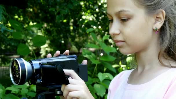 Chica joven mira en la cámara de vídeo en el fondo de fondo verde parque . — Vídeo de stock