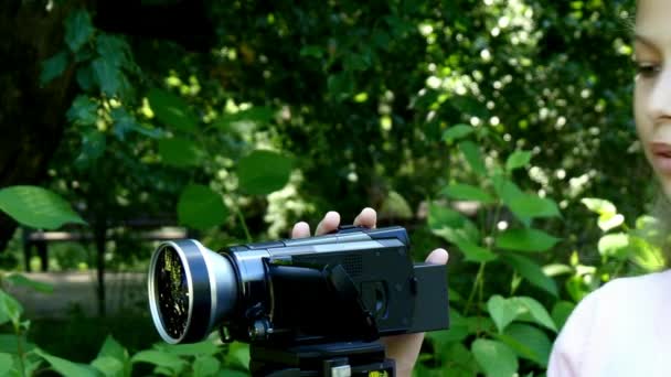 Jeune fille regarde dans la caméra vidéo sur fond de fond de parc vert . — Video