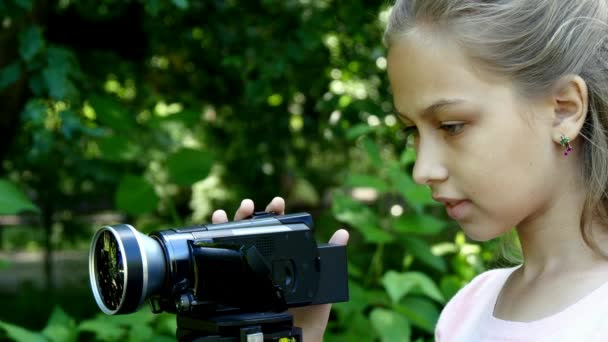 Young girl looks into video camera on background of green park background. — Stock Video