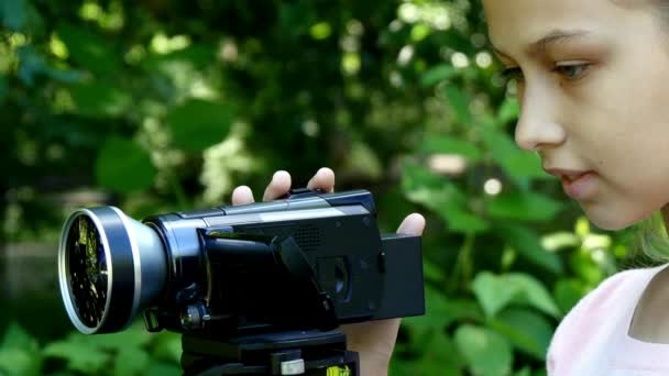 Chica joven mira en la cámara de vídeo en el fondo de fondo verde parque . — Vídeo de stock