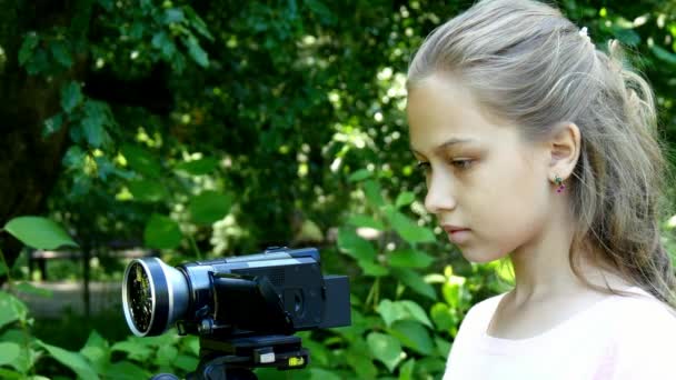 Young girl looks into video camera on background of green park background. — Stock Video