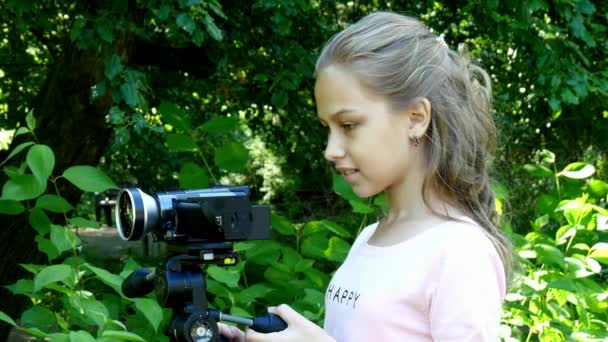 어린 소녀 녹색 공원 배경 배경 비디오 카메라에 보이는. — 비디오