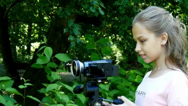 Jeune fille regarde dans la caméra vidéo sur fond de fond de parc vert . — Video