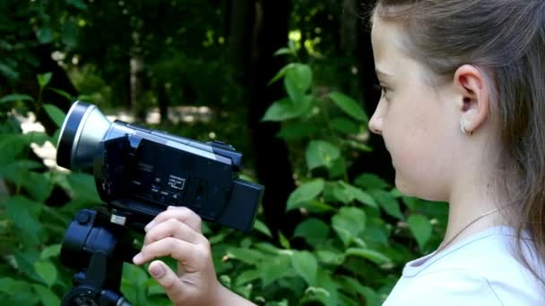 Jeune fille regarde dans la caméra vidéo sur fond de fond de parc vert . — Video