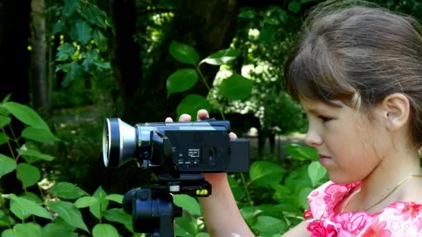 Νεαρή κοπέλα φαίνεται σε βίντεο κάμερα σε φόντο πράσινο πάρκο φόντο. — Αρχείο Βίντεο